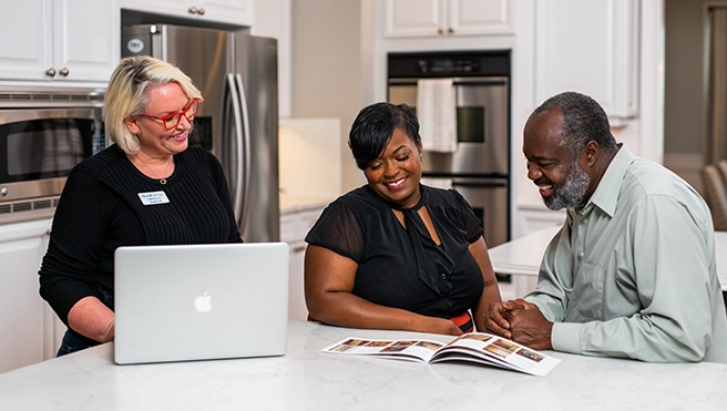 Couple and SHG employee reviewing papers and laptop.