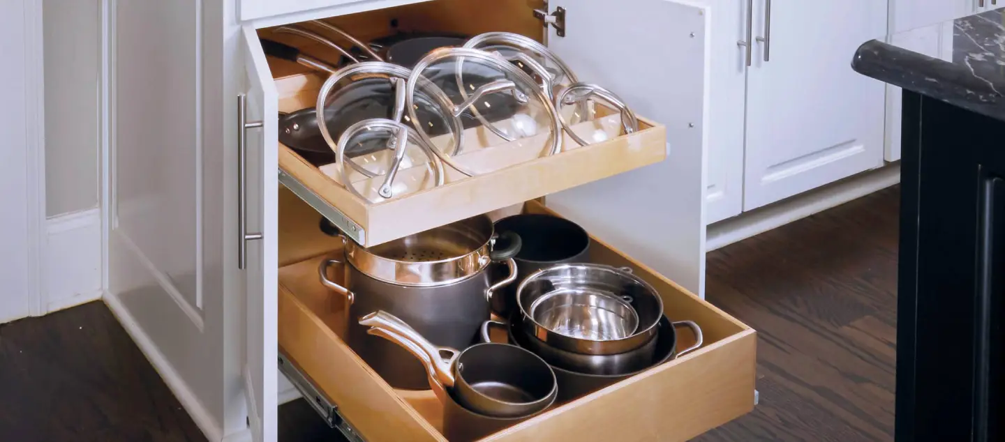 Two drawers in a kitchen cabinet pulled out to reveal neatly organized pots and pans.