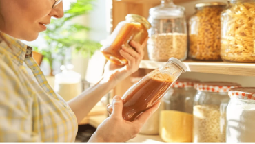 A lady holding a jar of sauce.