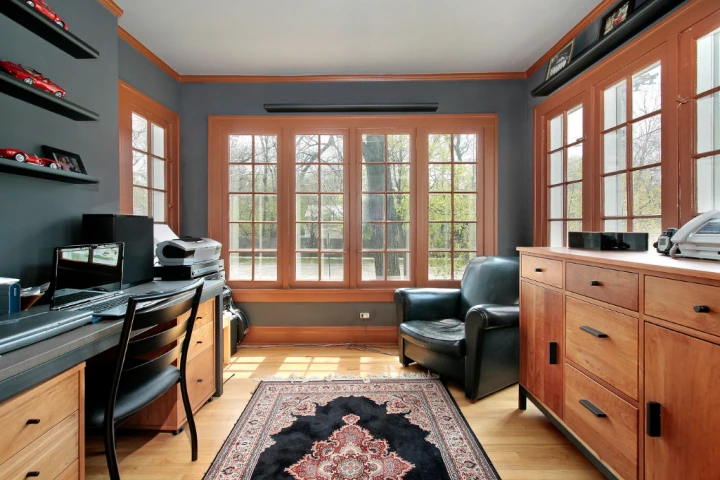 A room with a desk chair and a rug.