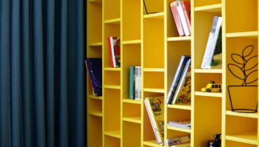 A yellow bookcase with books on it.